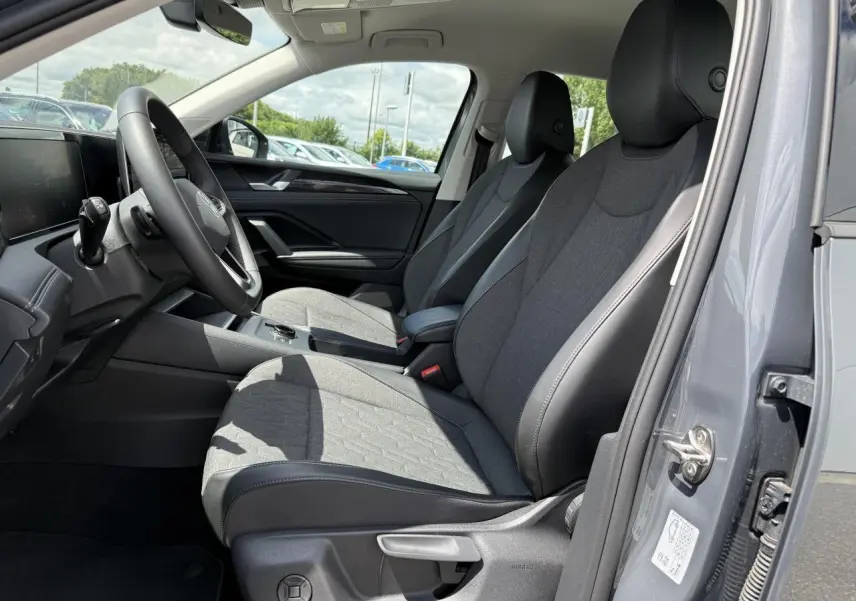 Vue intérieure côté conducteur du Volkswagen Tiguan 1.5 eHybrid gris Dauphin avec sièges tissu et cuir noir.