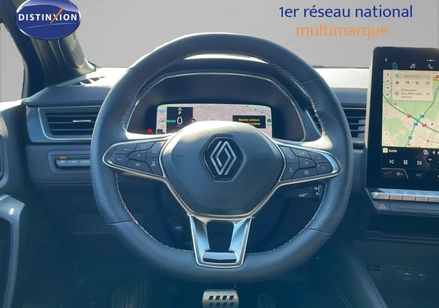 Vue centrée sur le volant du Renault Captur E-Tech hybride 2025, avec tableau de bord numérique et écran tactile visible.