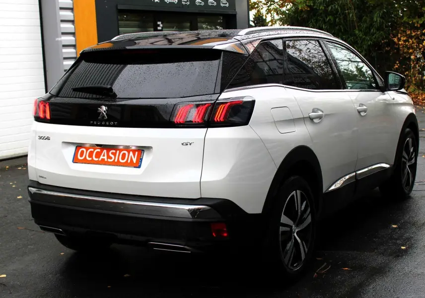 Vue 3/4 arrière droite d'un Peugeot 3008 blanc nacré avec toit panoramique noir et feux arrière LED distinctifs.