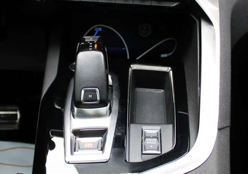 Gros plan sur la console centrale noire brillante du Peugeot 3008 2025 avec levier de vitesse automatique et bouton Drive Mode.