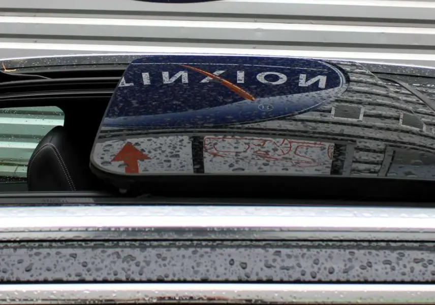 Toit panoramique ouvrant noir avec pluie sur un Peugeot 3008 blanc nacré, vue en gros plan sur l'ouverture.