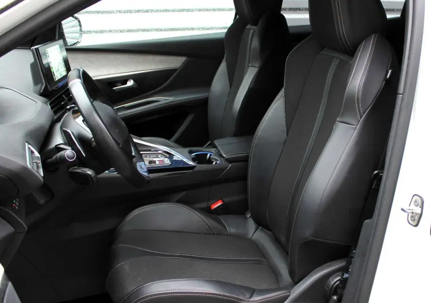 Intérieur côté conducteur du Peugeot 3008 blanc nacré 2025, sièges noirs en cuir avec surpiqûres contrastées et tableau de bord moderne.