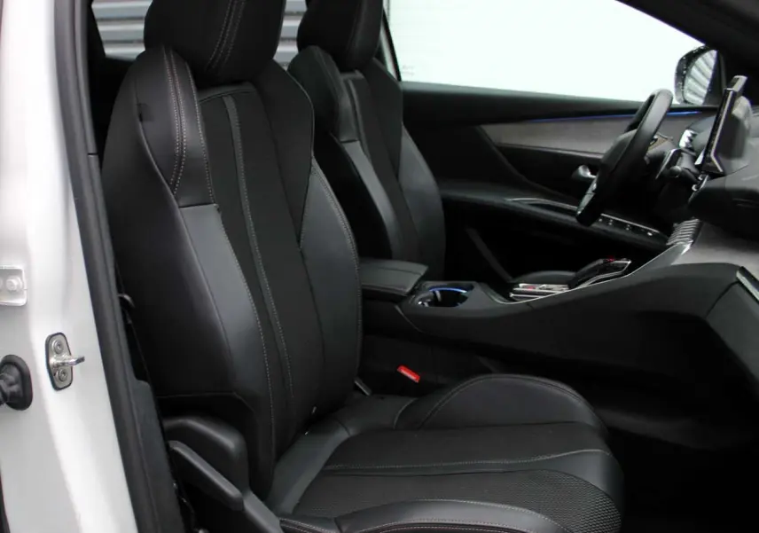 Vue intérieure côté conducteur du Peugeot 3008 blanc nacré 2025, sièges noirs en cuir et tableau de bord moderne.