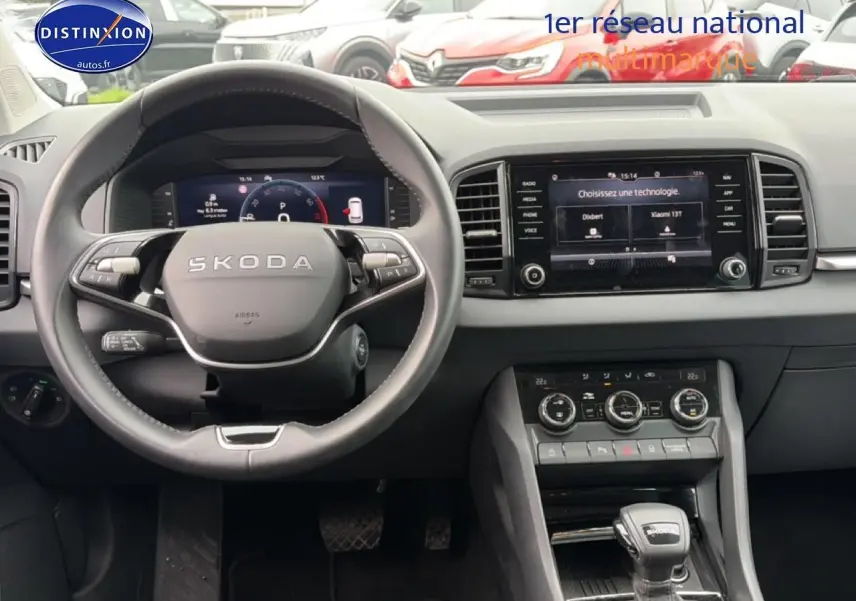Vue intérieure centrée sur le volant cuir SKODA et l'écran tactile du tableau de bord du Karoq noir 2025.