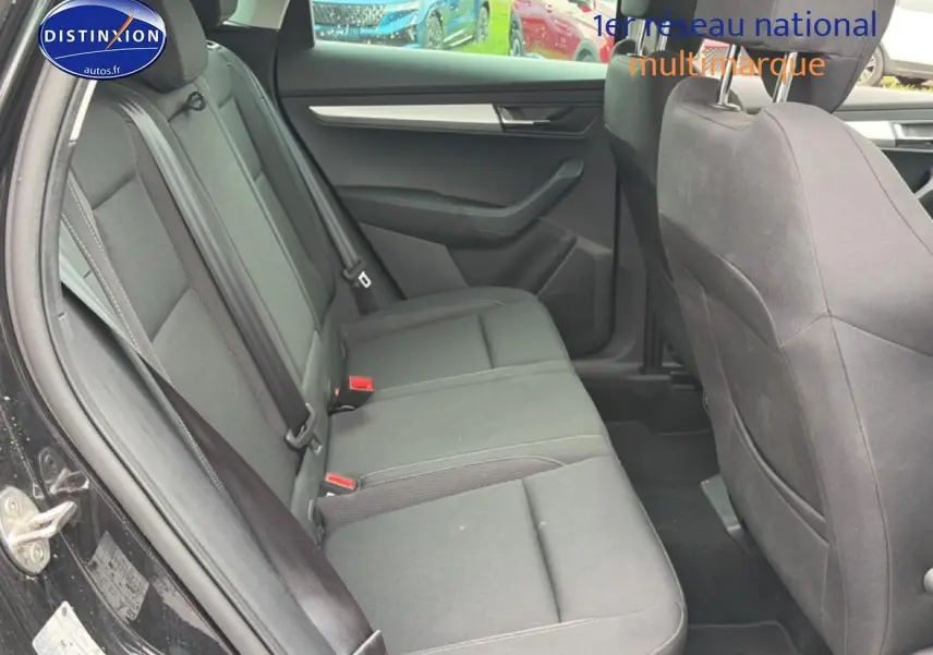 Vue latérale intérieure du siège arrière noir du Skoda Karoq 2025 avec ceintures et portes ouvertes.