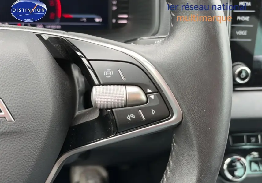 Gros plan sur les commandes à droite du volant cuir noir d’un Skoda Karoq 2025, avec tableau de bord et écran tactile en arrière-plan.