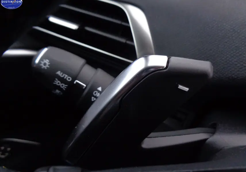 Gros plan sur la palette de changement de vitesse et la commande d'éclairage du Peugeot 3008 gris platinium métal 2023.