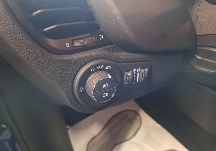 Gros plan sur la commande des phares et réglages d'éclairage du tableau de bord du FIAT 500X bleu 2024.