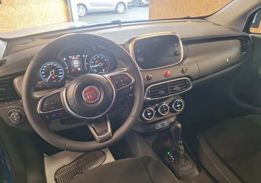 Intérieur noir de la Fiat 500X 2024 vu de face, avec tableau de bord digital et volant multifonctions.