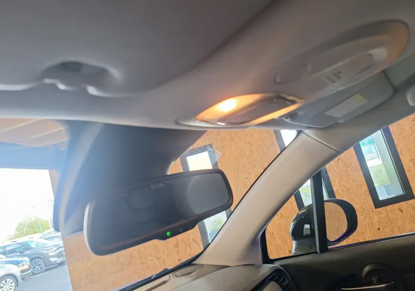 Vue intérieure du rétroviseur et du plafond avec lumière allumée du Fiat 500X 2024 bleu, côté droit visible par la fenêtre.