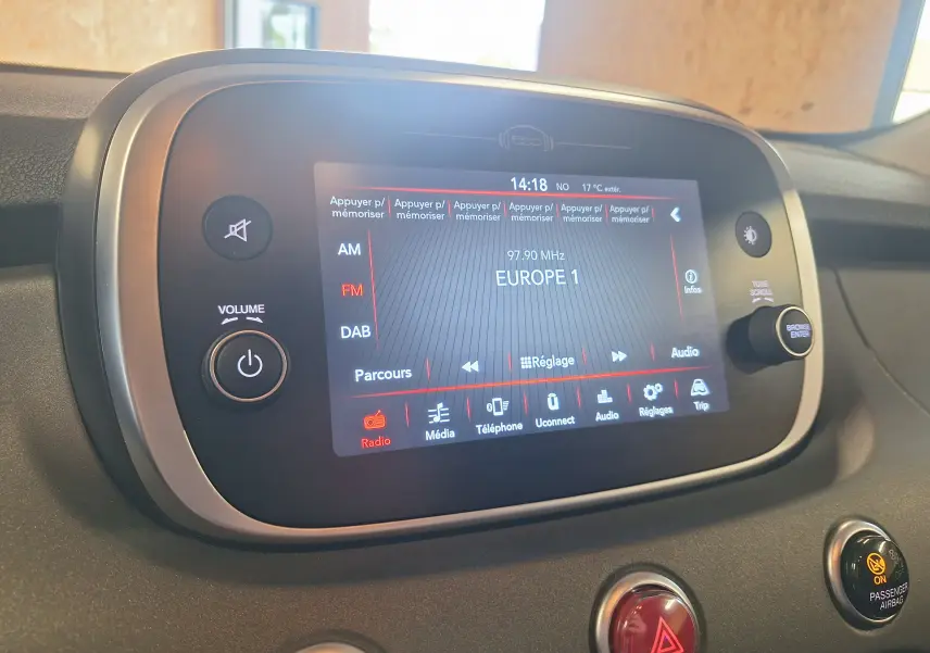 Écran tactile central de la FIAT 500X 2024 affichant la radio Europe 1 en FM, entouré de commandes de volume et réglages.