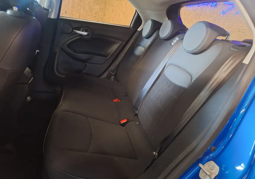 Banquette arrière noire vue côté gauche dans un FIAT 500X bleu 2024 avec appuie-têtes ronds et ceintures intégrées.
