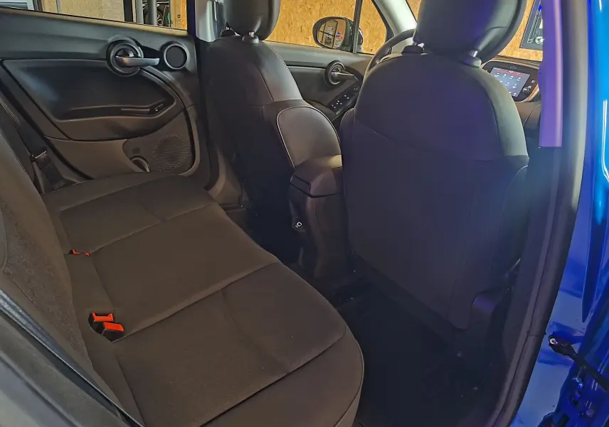 Vue intérieure arrière de la FIAT 500X bleu montrant la banquette noire et les dossiers des sièges avant.