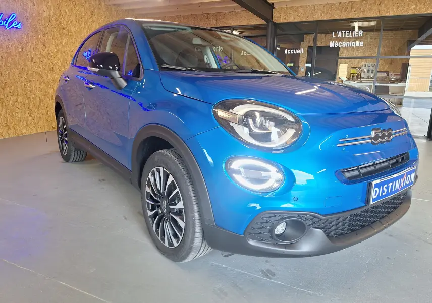 Vue 3/4 avant droite d'une FIAT 500X 2024 bleu métallisé avec phares LED et jantes alliage sport.