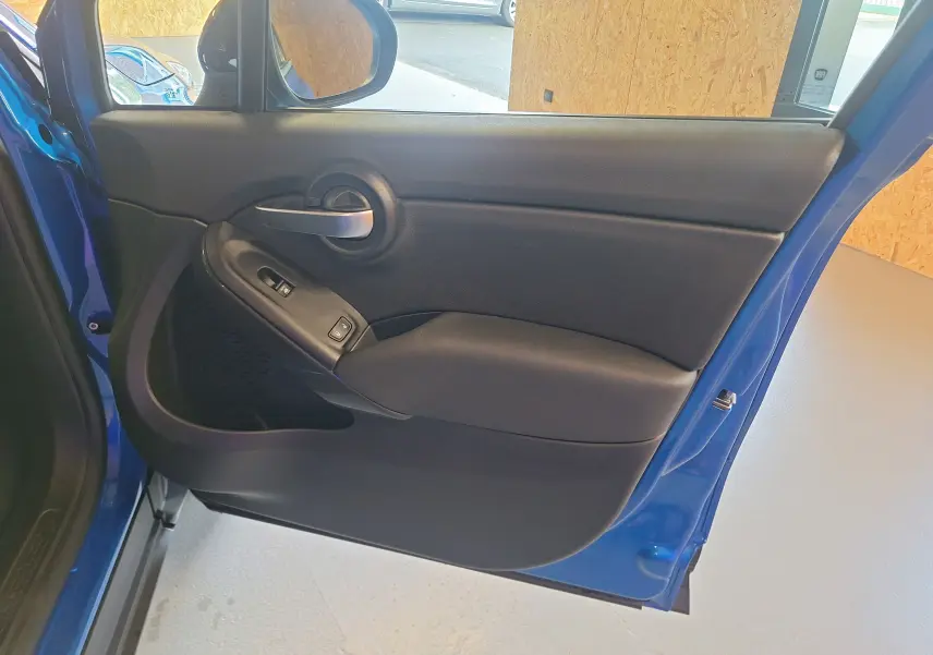 Intérieur côté gauche de la porte avant bleu métallisé du FIAT 500X 1.5 Firefly 130 Sport Pack 2024.