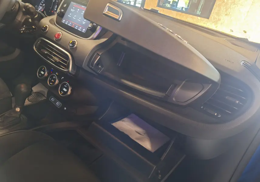 Intérieur du FIAT 500X 2024 bleu, vue côté passager montrant tableau de bord et boîte à gants ouverte.