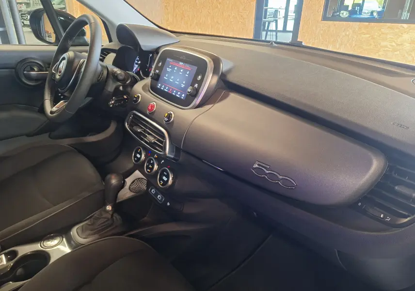 Intérieur noir de la Fiat 500X 2024, vue côté passager montrant tableau de bord et écran tactile central.