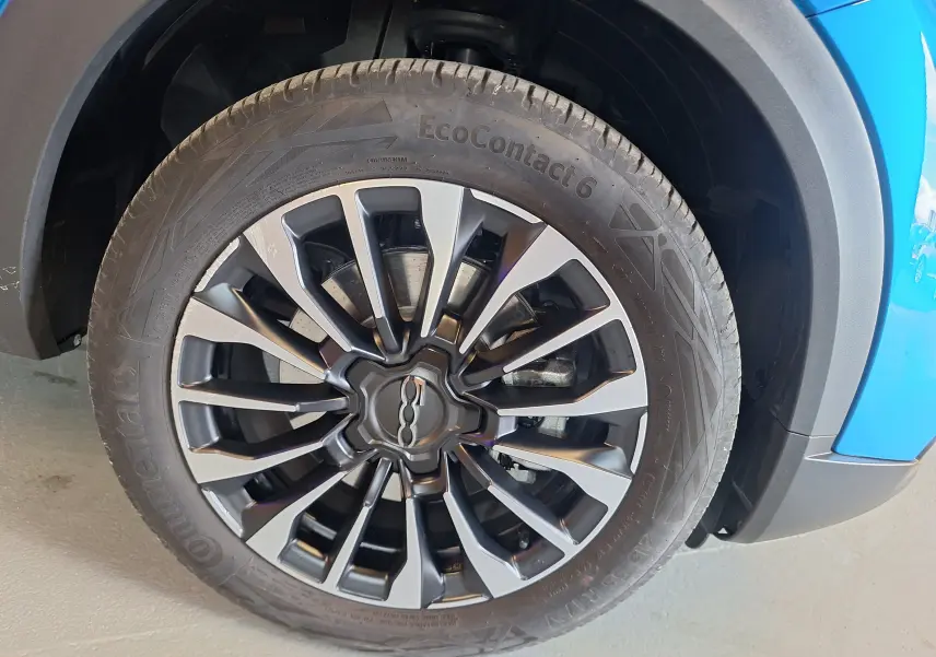 Gros plan sur la roue avant gauche bleu métallisé d'une Fiat 500X 2024 avec jante alliage au design moderne.