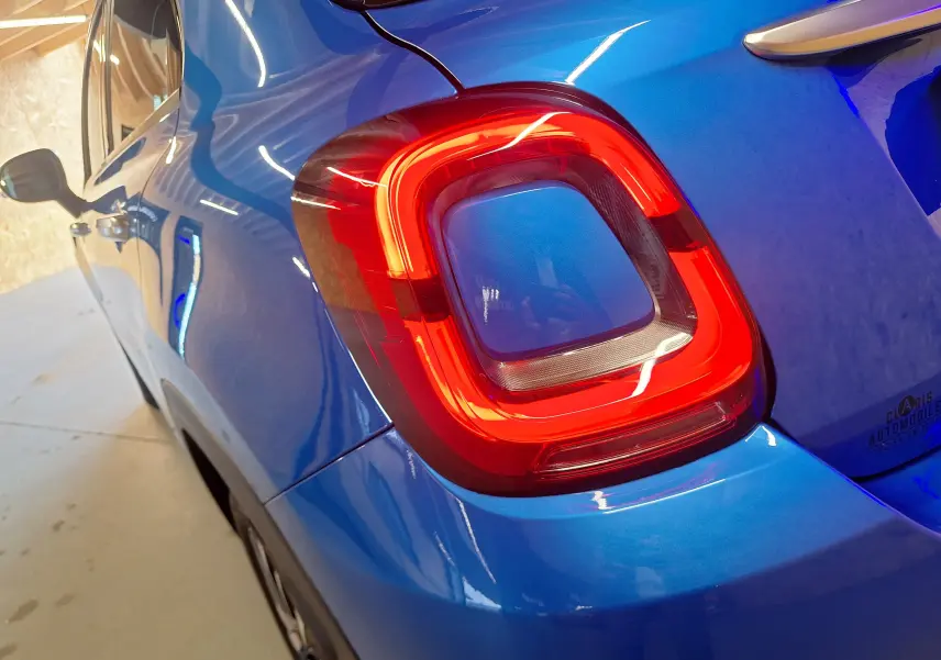 Gros plan sur le feu arrière droit rouge d'une FIAT 500X 2024 bleu métallisé, avec reflet intérieur visible.