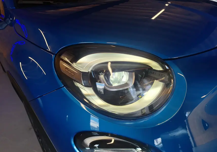 Gros plan sur le phare avant droit LED du FIAT 500X bleu métallisé 2024 avec logo 500 intégré.