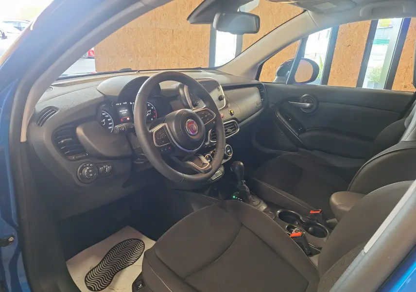 Intérieur avant droit du FIAT 500X bleu 2024, volant multifonctions, tableau de bord digital et sièges noirs.