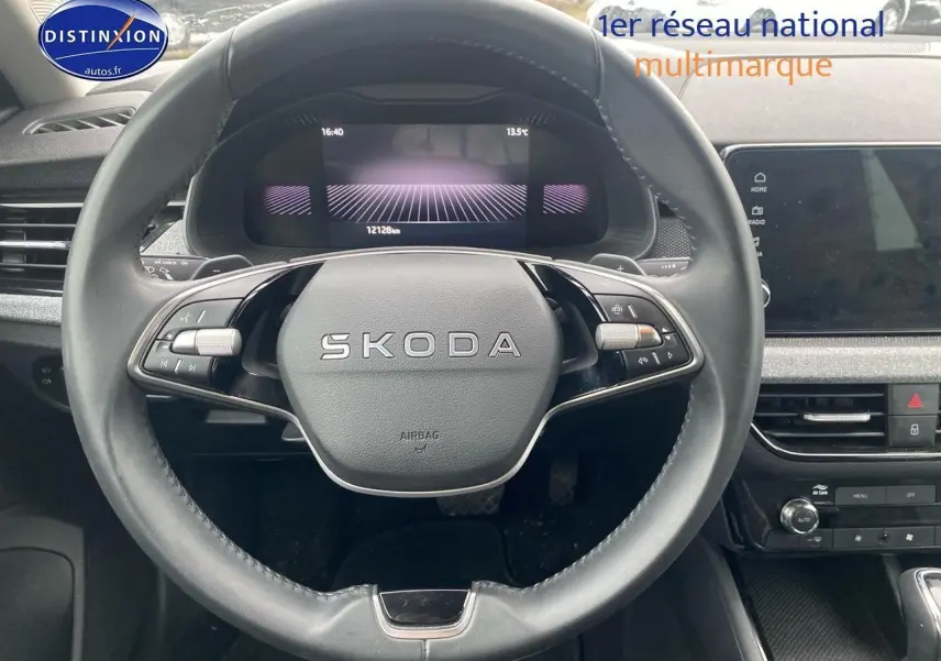 Vue rapprochée du volant cuir multifonction SKODA avec tableau de bord numérique et écran tactile central.
