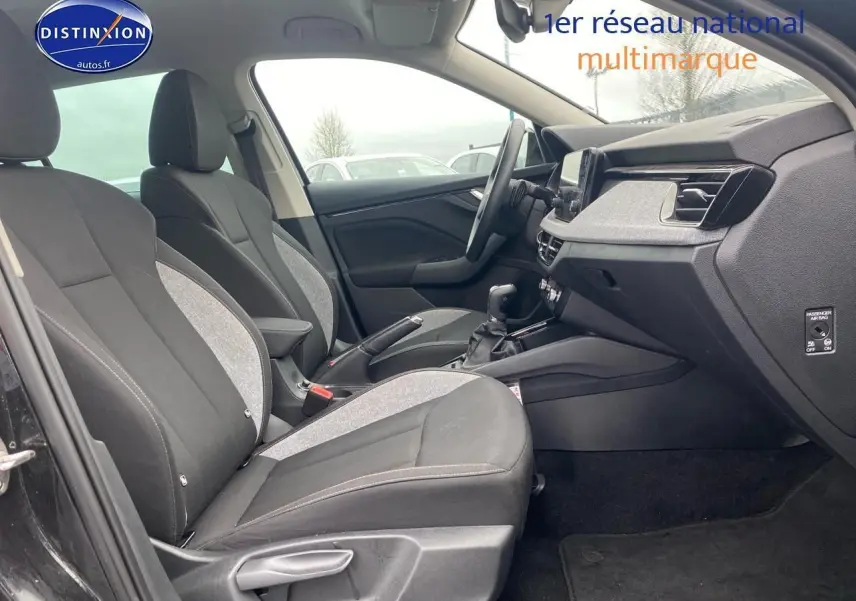 Vue intérieure côté gauche du Skoda Kamiq noir 2025, montrant sièges avant bi-matière et tableau de bord moderne.