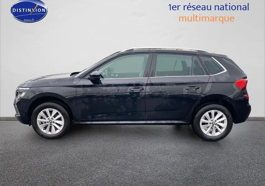 Profil latéral gauche d'un Skoda Kamiq noir 2025 avec jantes alu et barres de toit visibles.
