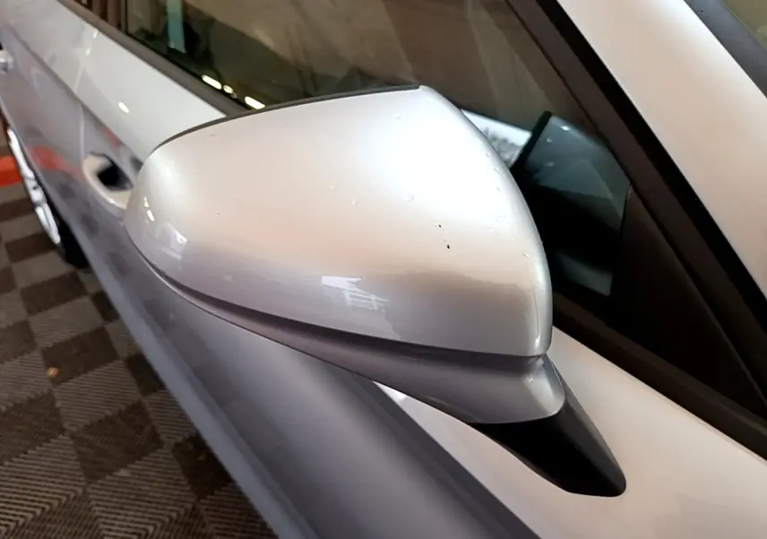 Gros plan sur le rétroviseur côté conducteur gris clair du SEAT Leon 2022, avec partie de la portière visible en gris foncé.