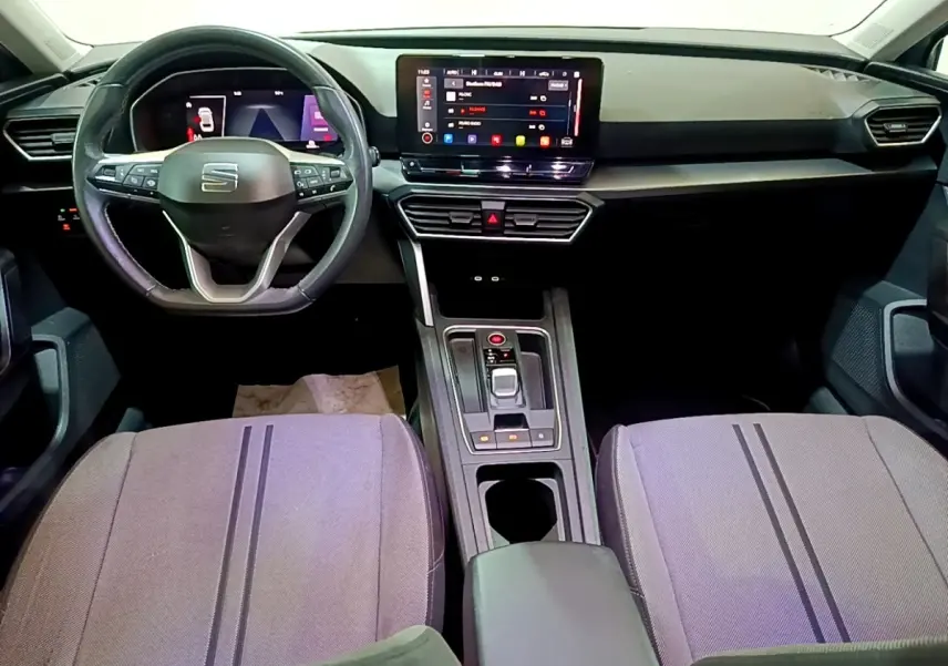 Vue intérieure avant du tableau de bord et volant cuir SEAT Leon gris foncé avec écran tactile central et commandes au volant.