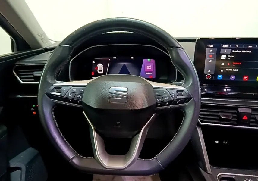 Vue intérieure centrée sur le volant cuir noir du SEAT Leon 2022 avec tableau de bord numérique et écran tactile.
