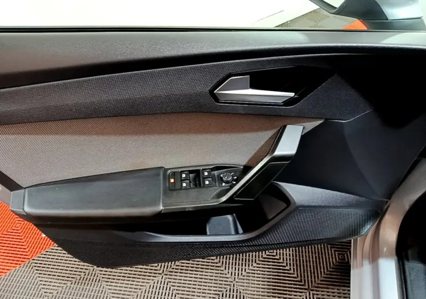 Vue rapprochée de la porte avant gauche grise du SEAT LEON 2022, avec commandes électriques et poignée noire.