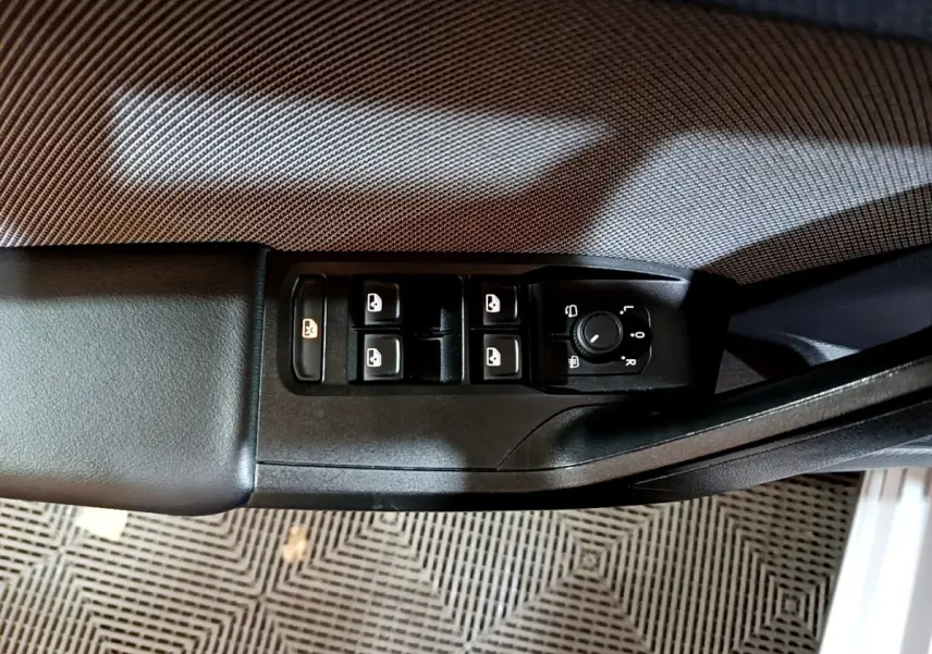 Vue rapprochée du panneau de commandes des vitres et rétroviseurs côté conducteur d’une SEAT Leon gris foncé.