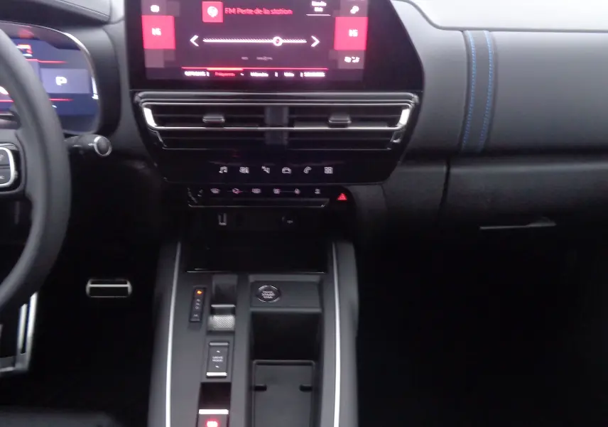 Tableau de bord et console centrale d'une Citroën C5 Aircross 2022 noire, avec écran tactile et coutures bleues visibles.