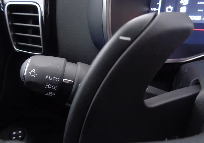 Gros plan sur la commande d'éclairage automatique à gauche du volant dans l'habitacle du Citroën C5 Aircross noir métal 2022.