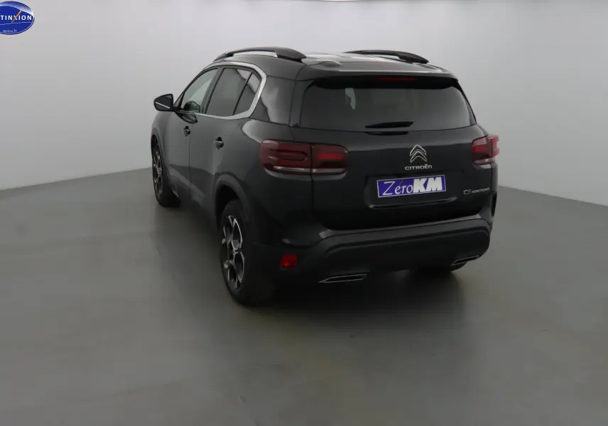 Vue 3/4 arrière gauche d'un Citroën C5 Aircross noir métal avec jantes bi-ton et toit ouvrant en studio.