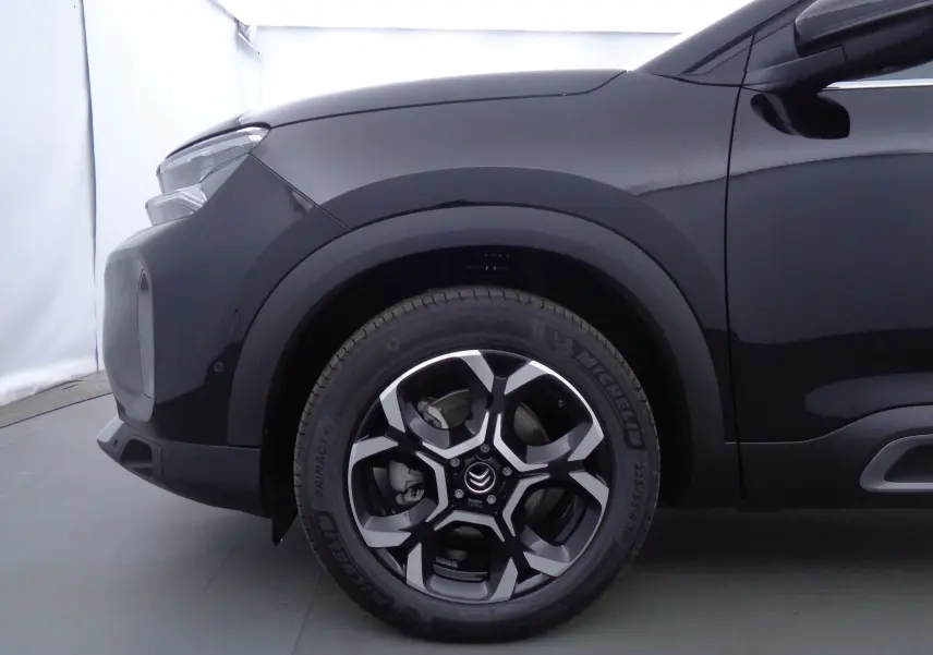 Gros plan sur la roue avant gauche du Citroën C5 Aircross noir métal 2022 avec jante alliage bicolore.