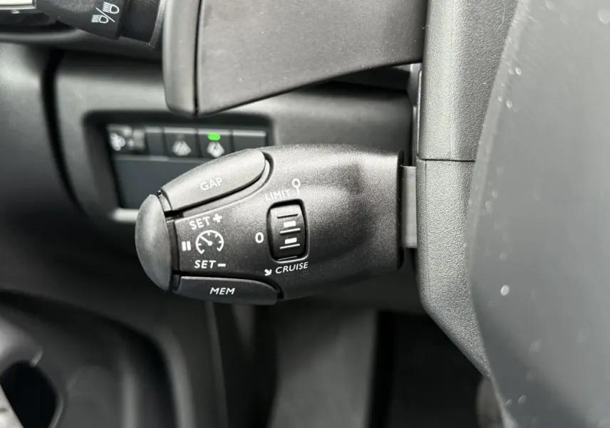 Gros plan sur la commande de régulateur de vitesse au volant d'un Citroën C5 Aircross Hybrid noir.