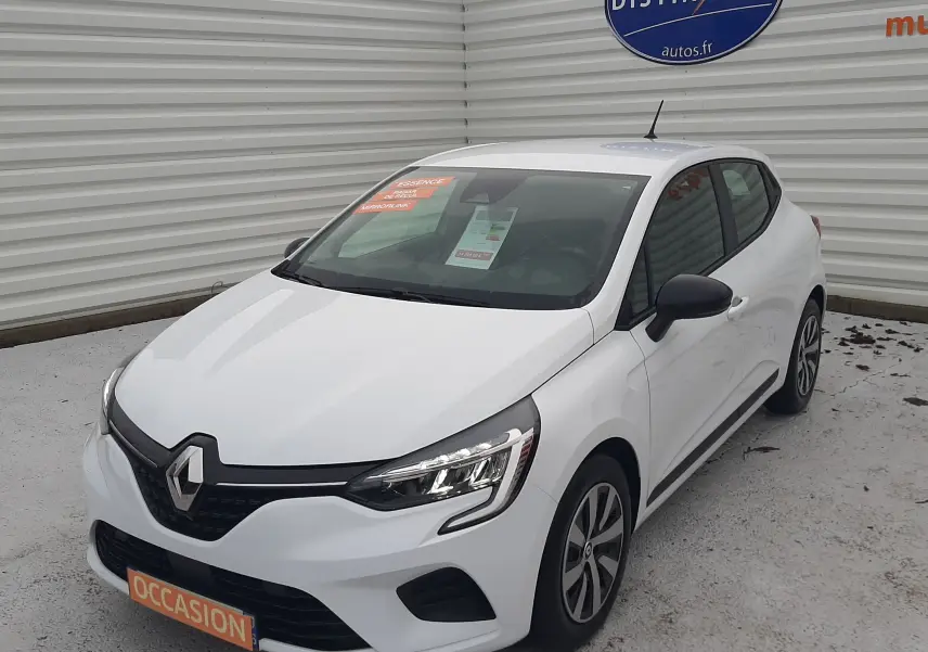 Renault Clio V blanche vue en 3/4 avant droit, avec phares LED et rétroviseurs noirs, stationnée devant un mur métallique.