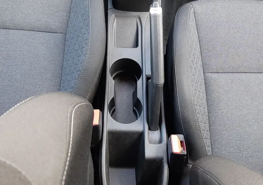 Vue plongeante sur la console centrale noire de la Renault Clio V avec frein à main manuel et sièges tissu noir.