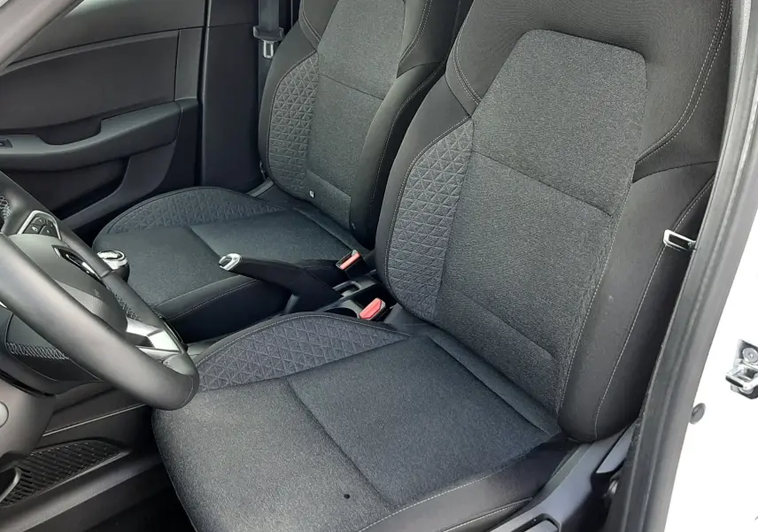 Vue intérieure côté conducteur de la Renault Clio V blanche, mettant en valeur les sièges avant en tissu noir avec motifs géométriques.