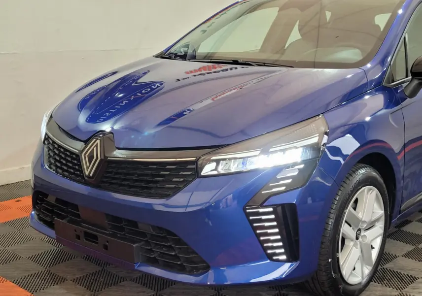 Vue 3/4 avant droit d'une Renault Clio Evolution Blue dCi 100 bleu avec phares LED allumés et jantes argentées.