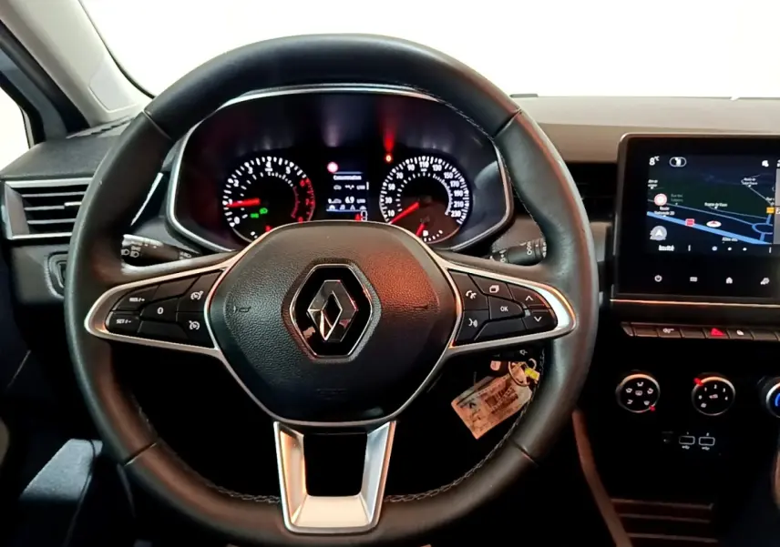 Vue intérieure centrée sur le volant cuir noir de la Renault Clio Business avec tableau de bord et écran tactile visible à droite.