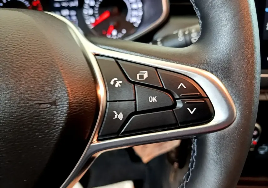 Gros plan sur les commandes multifonctions à droite du volant cuir noir de la Renault Clio Business blanche de 2021.