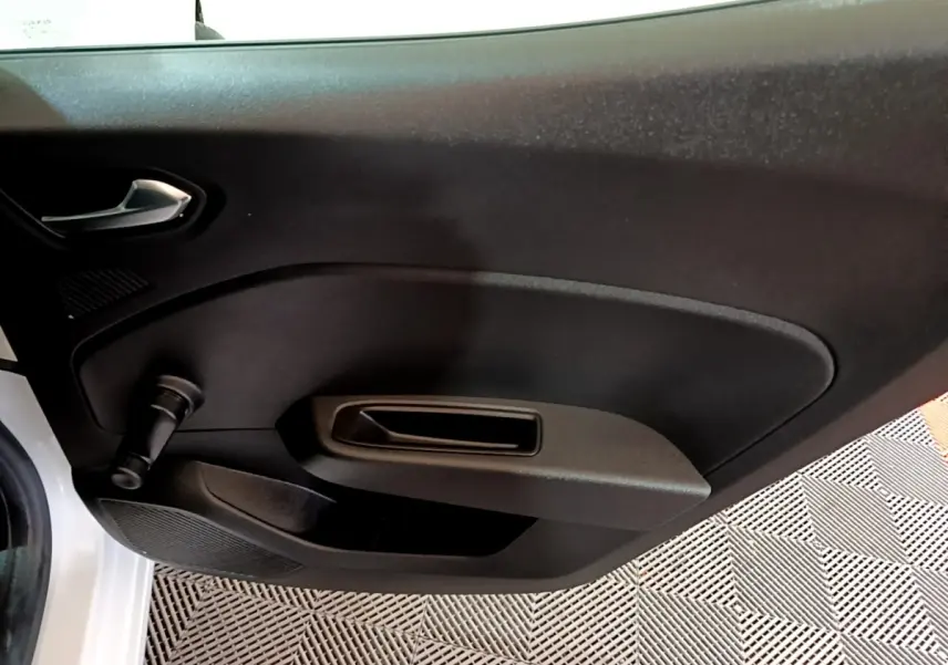 Vue rapprochée de la porte intérieure côté gauche d’une Renault Clio Business blanche, avec manivelle de vitre.