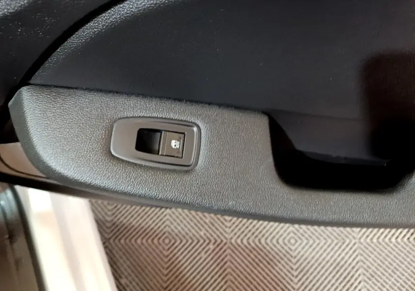 Gros plan sur le bouton de verrouillage des portes côté gauche de la porte intérieure d'une Renault Clio blanche.
