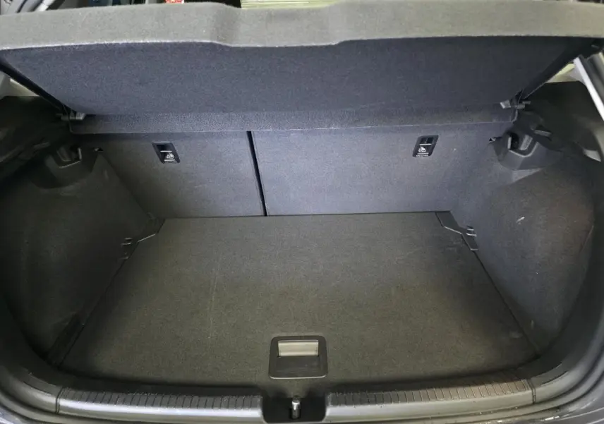 Coffre ouvert vu de l'arrière d'une Volkswagen Polo gris, montrant un espace de chargement propre et vide.