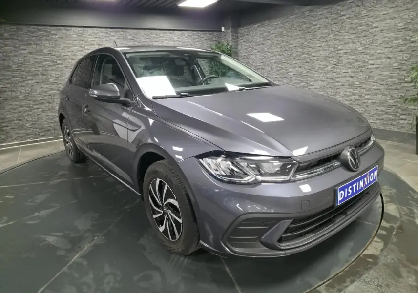 Volkswagen Polo gris métallisé vue 3/4 avant droit en intérieur avec jantes alliage et calandre chromée.