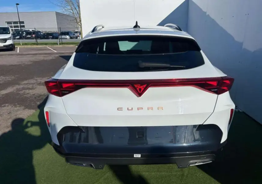 Vue arrière d'une CUPRA Formentor blanche 2025 avec signature lumineuse rouge et logo central distinctif.