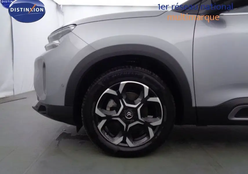 Gros plan sur la roue avant gauche du Citroën C5 Aircross gris Artense avec jante alliage bicolore au design moderne.